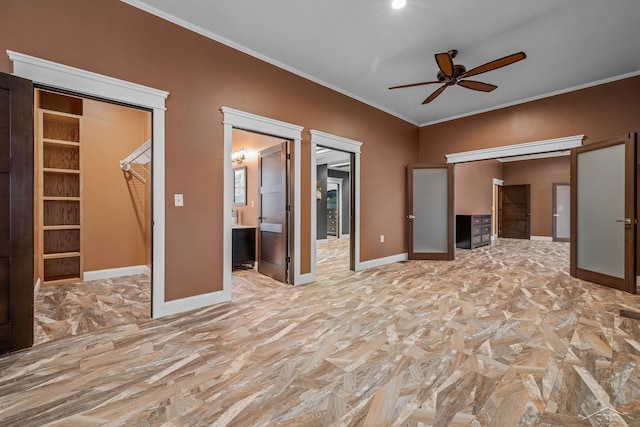 unfurnished bedroom with a closet, ensuite bath, a walk in closet, baseboards, and ornamental molding