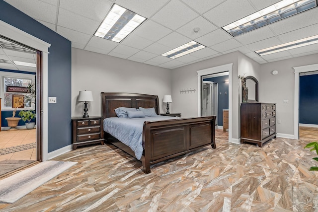 bedroom with a paneled ceiling and baseboards