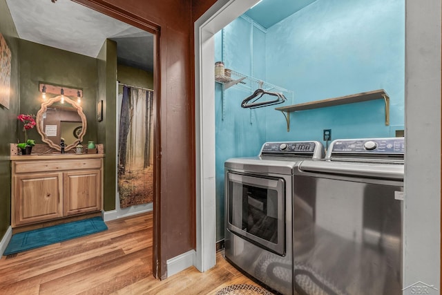 washroom with light wood-style floors, washing machine and dryer, laundry area, and baseboards