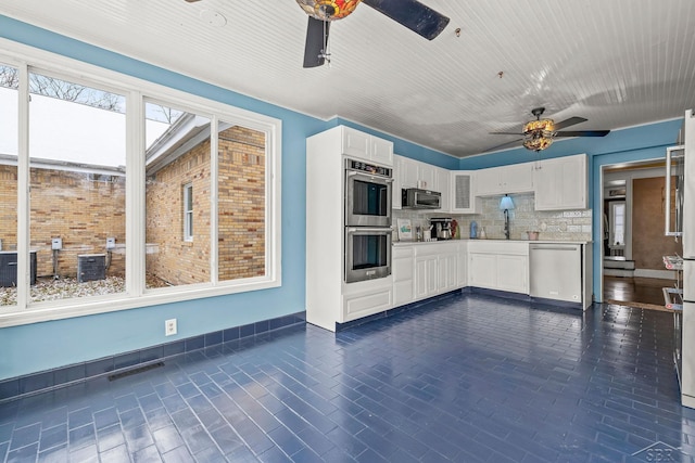 kitchen featuring tasteful backsplash, white cabinets, a sink, appliances with stainless steel finishes, and ceiling fan