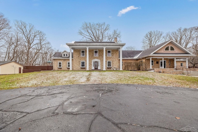 neoclassical home with a porch, brick siding, and a chimney