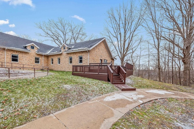 back of property featuring a yard, brick siding, and a wooden deck