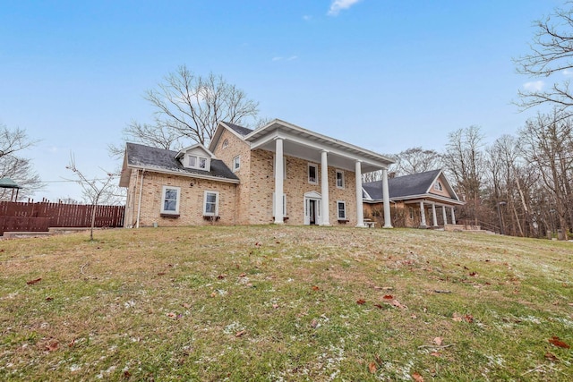 greek revival house with brick siding, fence, and a front lawn