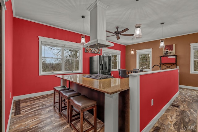 kitchen featuring stainless steel fridge, ceiling fan, island exhaust hood, baseboards, and crown molding