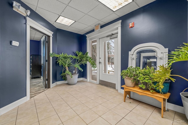 interior space featuring tile patterned flooring, baseboards, and a drop ceiling