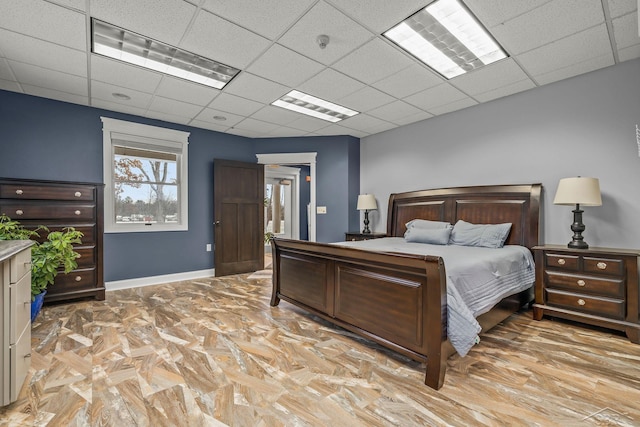 bedroom featuring a paneled ceiling and baseboards