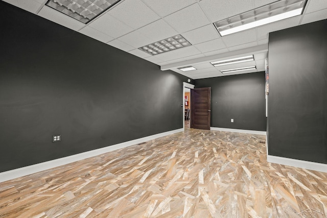 spare room featuring a drop ceiling and baseboards