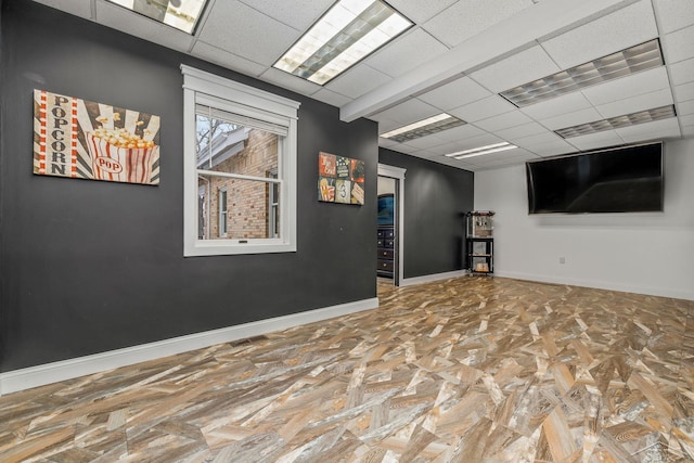 below grade area with a drop ceiling and baseboards