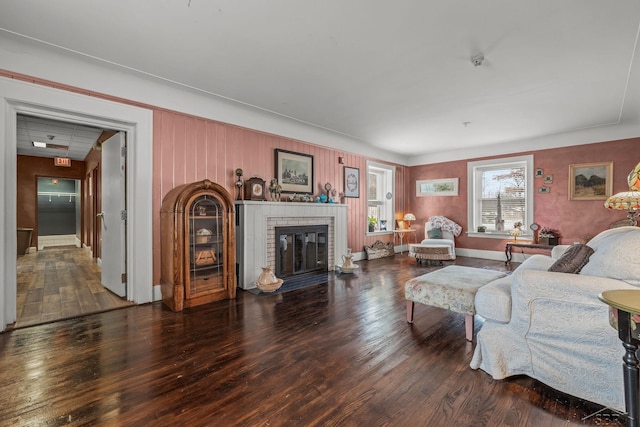 living room with a brick fireplace, wood finished floors, and baseboards