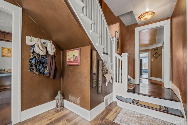 stairway with visible vents, wood finished floors, and baseboards