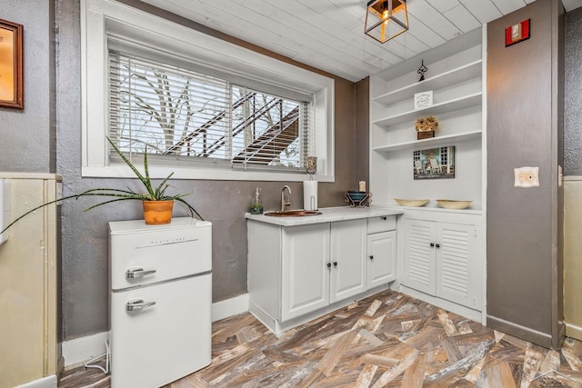 interior space featuring wood ceiling, light countertops, white cabinetry, open shelves, and a sink