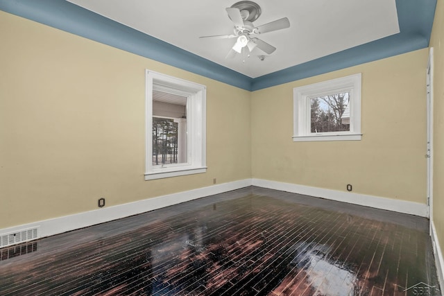 unfurnished room featuring a ceiling fan, visible vents, baseboards, and dark wood-style flooring