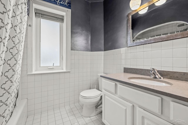 full bath featuring a wainscoted wall, tile walls, toilet, vanity, and tile patterned floors