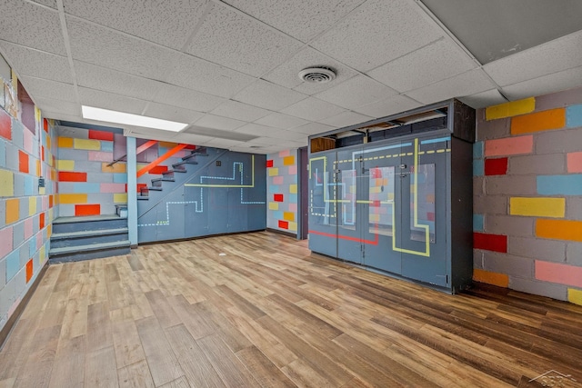 interior space featuring concrete block wall, stairs, visible vents, and wood finished floors