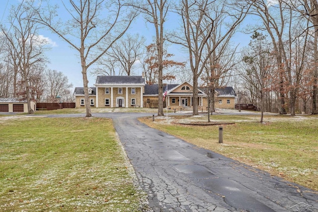 greek revival inspired property featuring aphalt driveway, a front yard, and brick siding