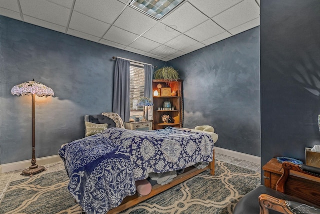 bedroom featuring a paneled ceiling and baseboards