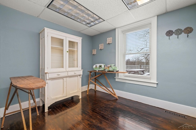 interior space with dark wood-style floors, a paneled ceiling, and baseboards