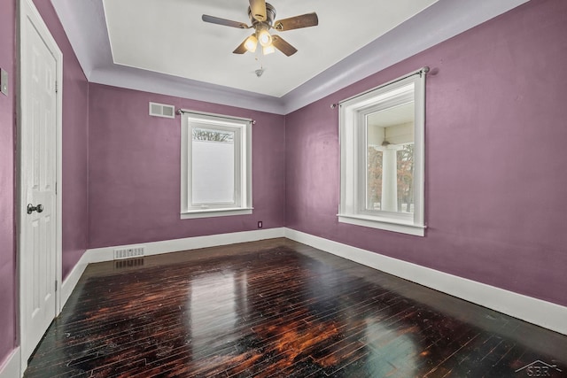 spare room with dark wood-style floors, visible vents, baseboards, and a ceiling fan