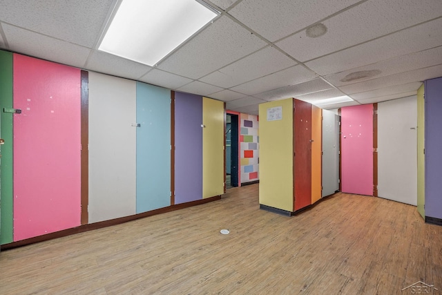 unfurnished room with a drop ceiling, wood finished floors, and baseboards