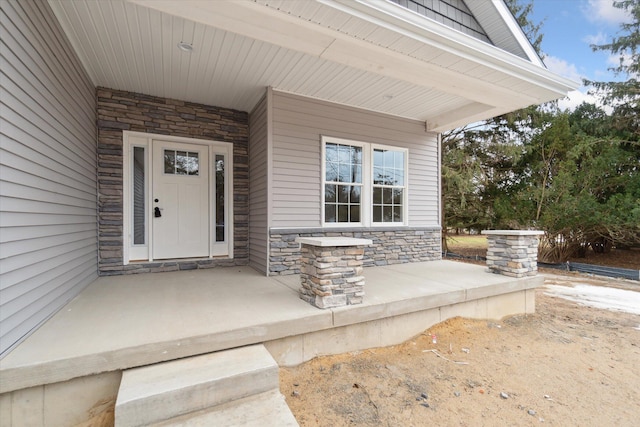 doorway to property featuring stone siding and covered porch