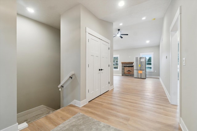 corridor with light wood-style floors, recessed lighting, baseboards, and an upstairs landing