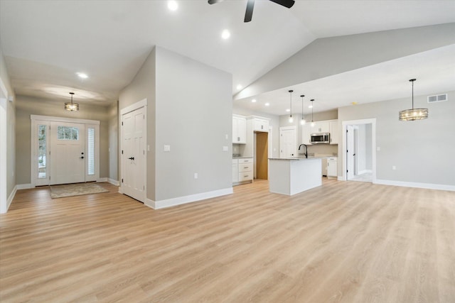 unfurnished living room with light wood-type flooring, visible vents, and baseboards