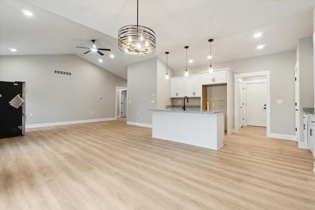 kitchen with visible vents, light wood-style flooring, freestanding refrigerator, vaulted ceiling, and a sink