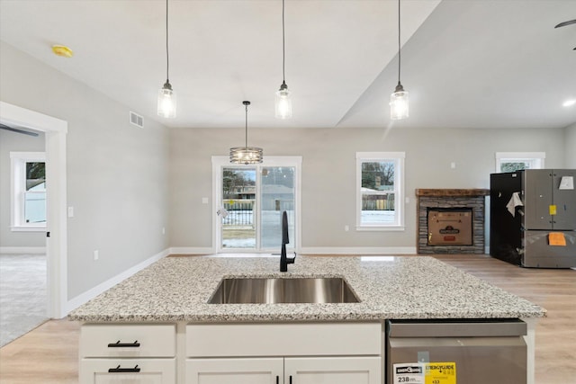 kitchen featuring freestanding refrigerator, open floor plan, white cabinets, a sink, and dishwasher