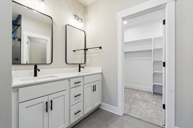 bathroom featuring double vanity, a sink, and a walk in closet