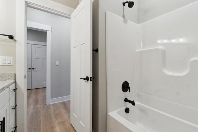 bathroom featuring tub / shower combination, vanity, baseboards, and wood finished floors