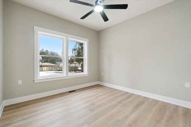 spare room with light wood finished floors, visible vents, and baseboards