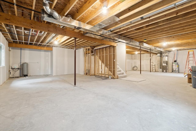 unfinished basement featuring heating unit, water heater, and stairs