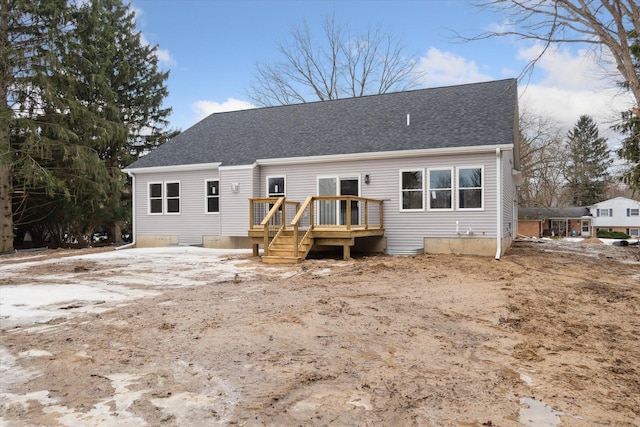 rear view of house featuring a shingled roof and a wooden deck