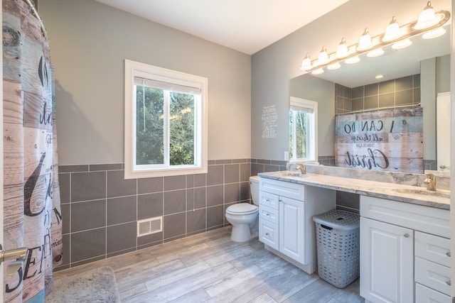 bathroom with tile walls, wood finished floors, visible vents, and a sink