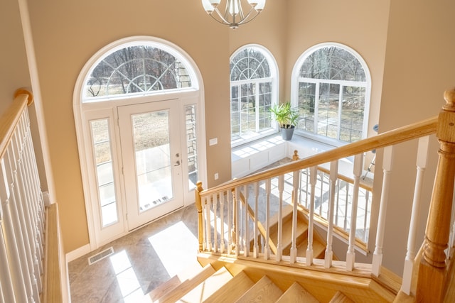 foyer entrance featuring visible vents, a high ceiling, an inviting chandelier, and stairway