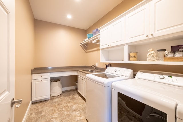 laundry area featuring washer and dryer, cabinet space, baseboards, and a sink