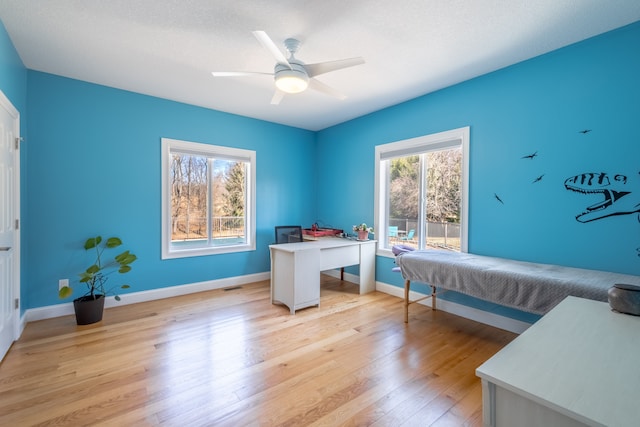 bedroom with visible vents, light wood-style flooring, a ceiling fan, and baseboards