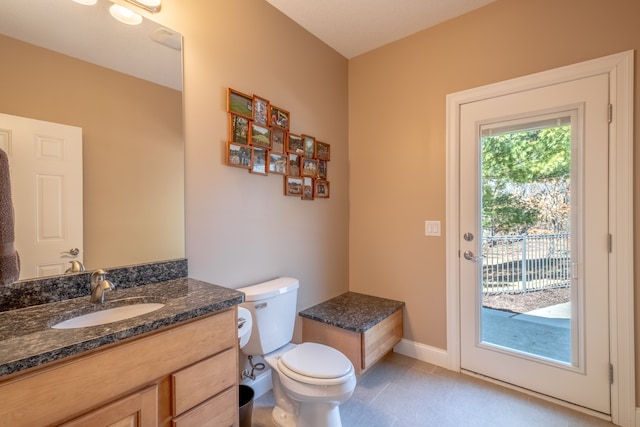 half bath with vanity, toilet, baseboards, and tile patterned flooring