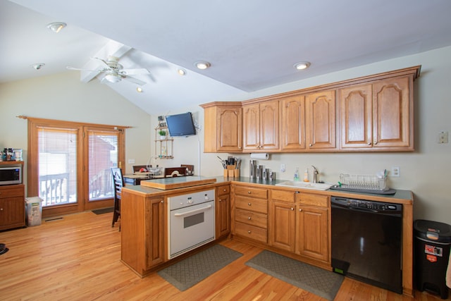 kitchen with a peninsula, a sink, light wood-style floors, black dishwasher, and white oven