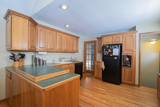 kitchen featuring recessed lighting, a sink, light wood-type flooring, a peninsula, and black appliances