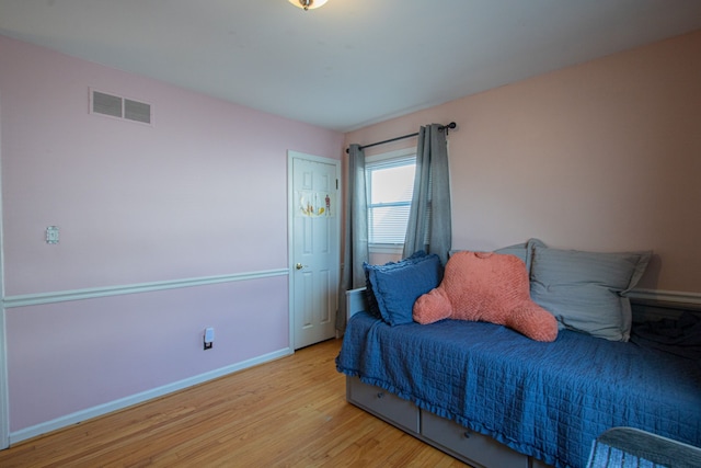 bedroom featuring baseboards, visible vents, and wood finished floors