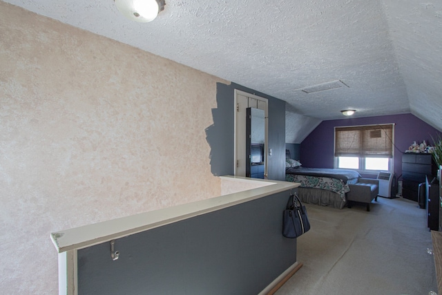 unfurnished bedroom featuring vaulted ceiling, carpet floors, a textured ceiling, and visible vents