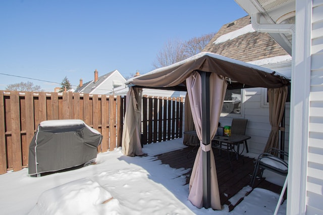 snow covered deck featuring a grill and fence