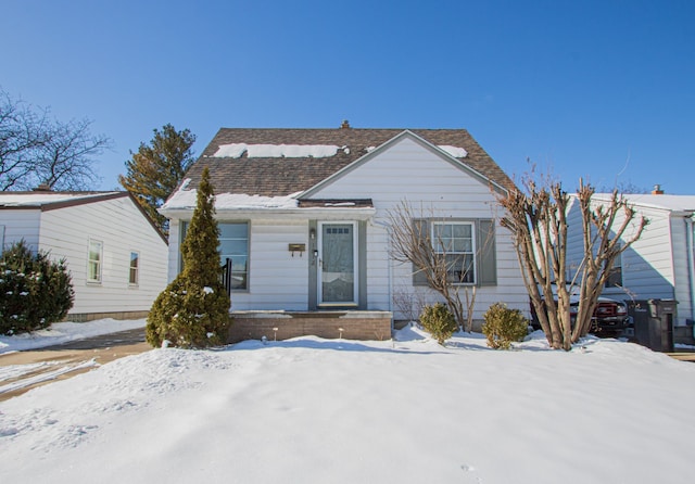 bungalow-style home with roof with shingles