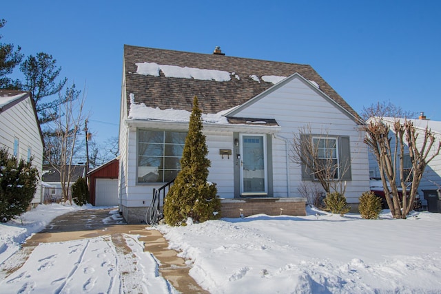 view of front of property with roof with shingles, a detached garage, and an outdoor structure