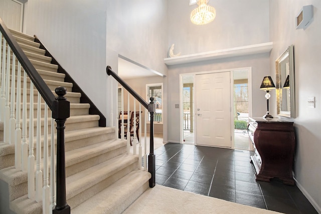 foyer featuring stairway, baseboards, a notable chandelier, and a towering ceiling