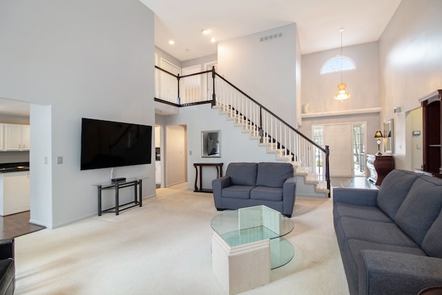 living room featuring light carpet, visible vents, stairway, and a wealth of natural light