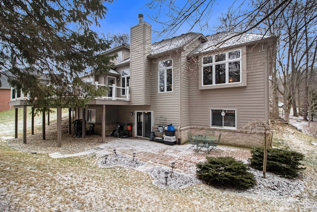 rear view of property with a patio area, a chimney, and brick siding