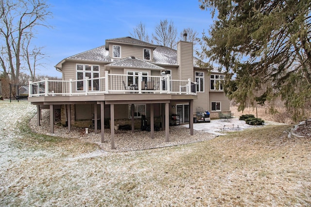 back of property featuring roof with shingles, a deck, and a chimney