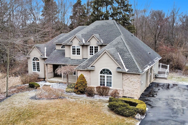 traditional-style house featuring brick siding, driveway, a shingled roof, and a front yard